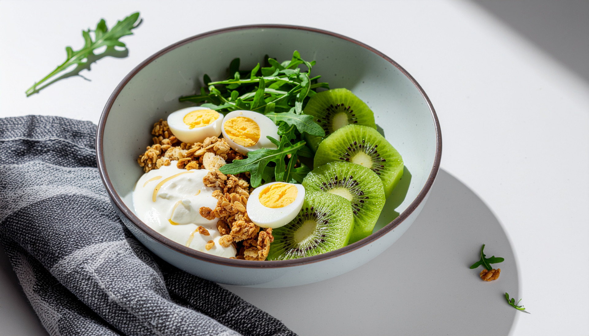 Breakfast bowl with kiwi, arugula, eggs, yogurt and granola