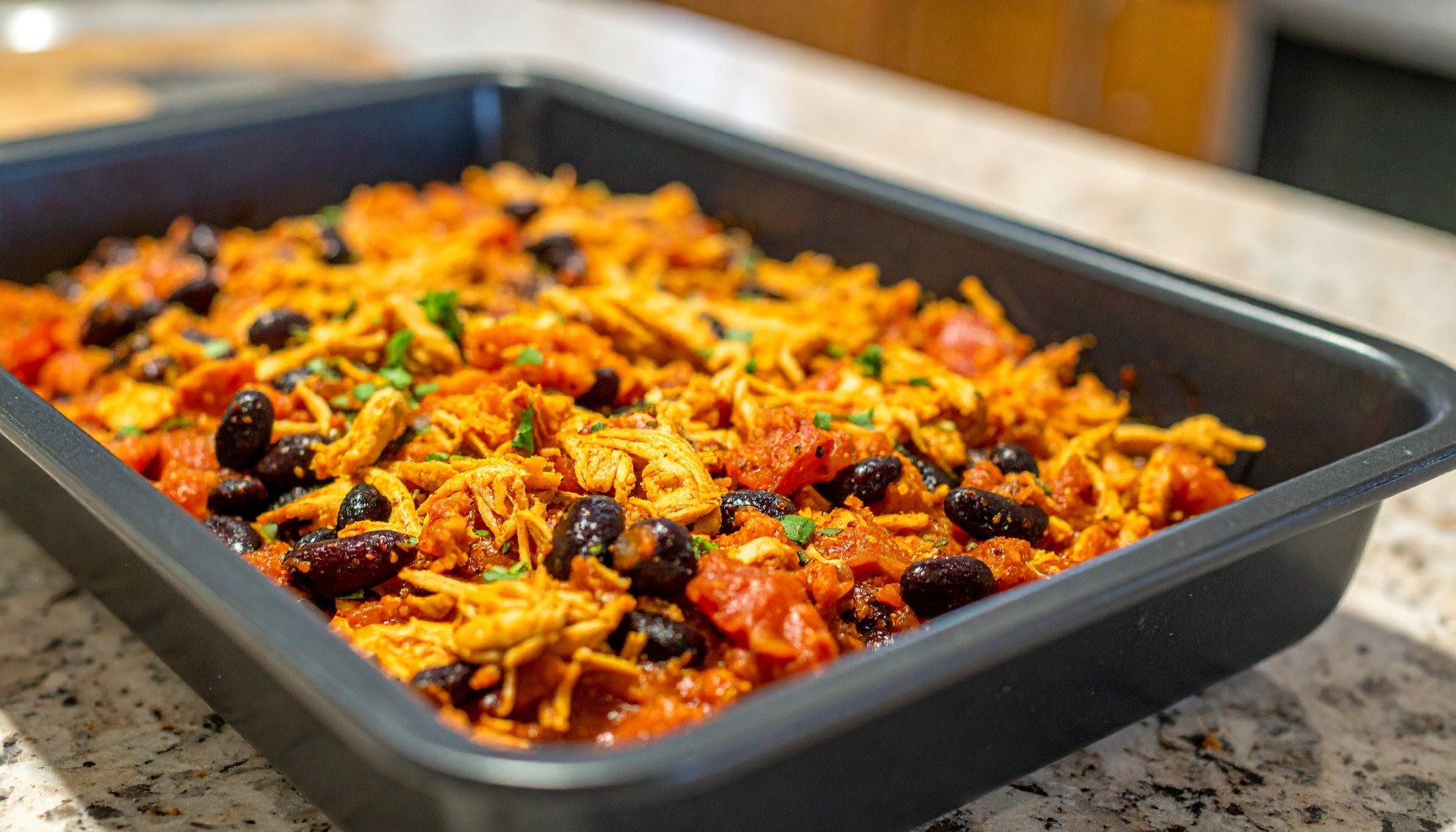 Baked salsa shredded chicken with black beans in a baking pan